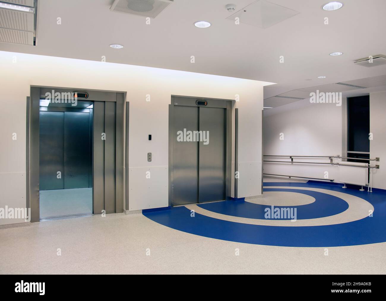 Aufzüge im Atrium eines neuen modernen Krankenhauses, blaue Muster auf dem Boden Stockfoto