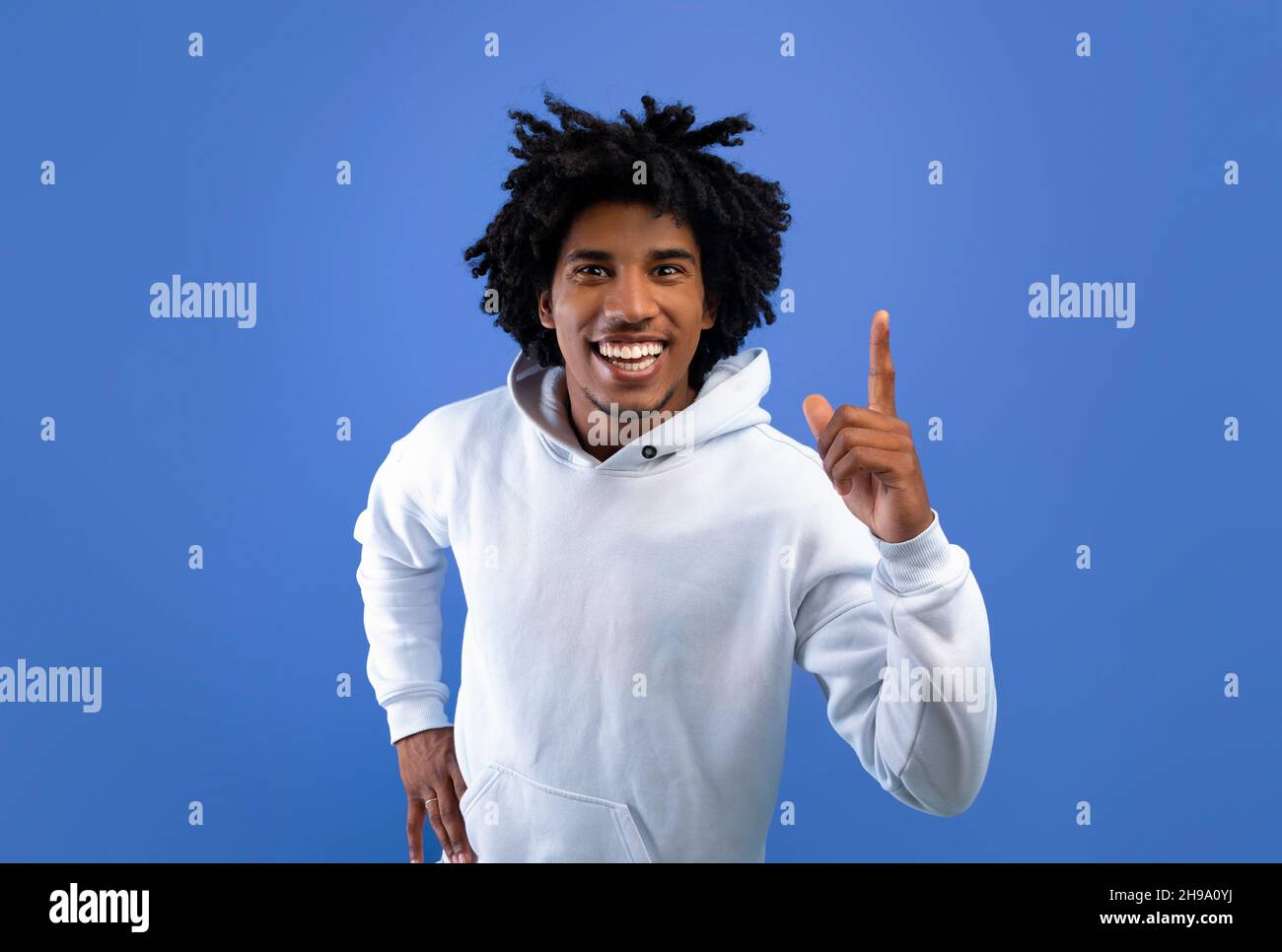 Cooler schwarzer Teenager, der eine kreative Idee hat, nach oben zeigt und den AHA-Moment auf blauem Studiohintergrund erlebt Stockfoto