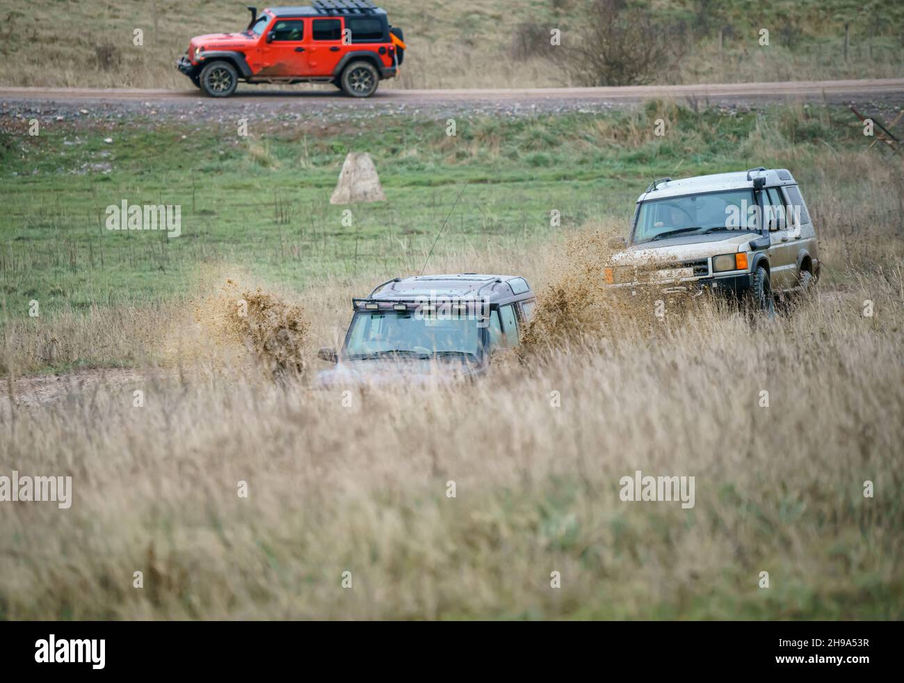 Geländewagen im Geländewagen, die über Schlamm und Wasser geloggte Gelände fahren, Salisbury Plain Wilts UK. Land Rover, Jeep Rubicon, Cherokee, Mitsubishi, Suzuki Stockfoto