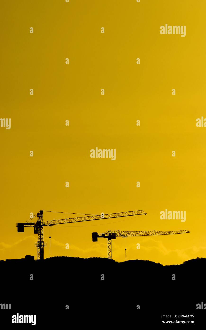 Bauindustrie und Entwicklung. Kran bei der Arbeit gegen goldenen Sonnenuntergang Himmel (mit Kopierraum) Stockfoto