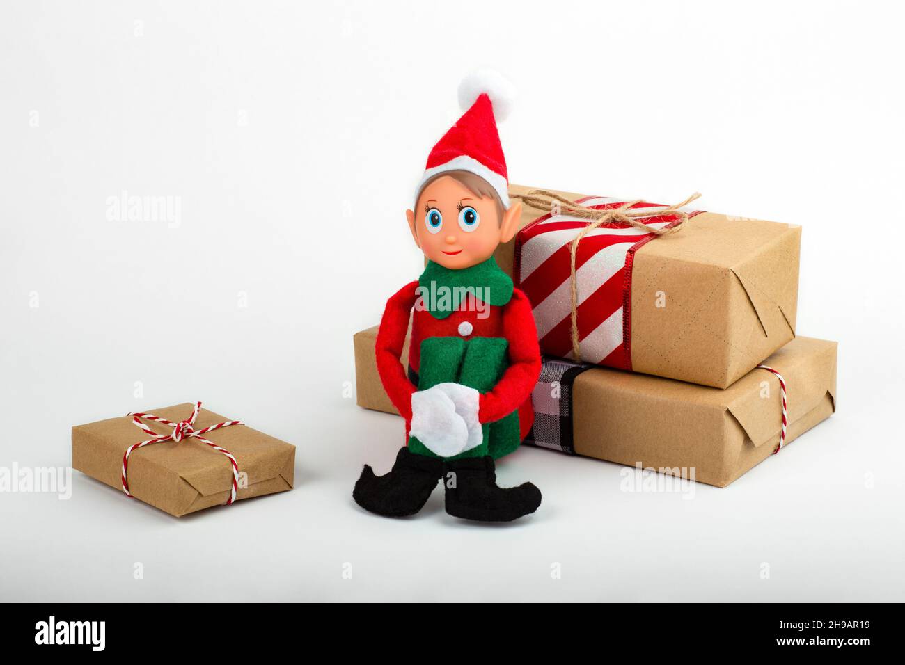 Weihnachts-Elf-Spielzeug mit Geschenkschachteln auf weißem Hintergrund mit Kopierfläche. Weihnachtsstimmung, Weihnachtstradition. Stockfoto