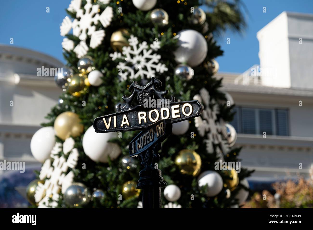 Nahaufnahme des Straßenschildes an der berühmten Kreuzung von Rodeo Drive und Via Rodeo mit dem Weihnachtsbaum im Hintergrund Stockfoto