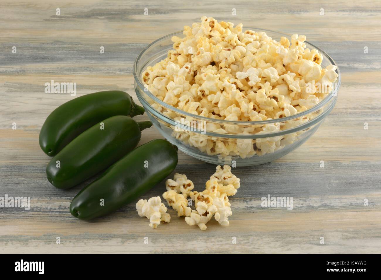 Popcorn mit Jalapeno-Pfeffer in einer Glas-Snack-Schüssel mit frischem Jalapenos Stockfoto