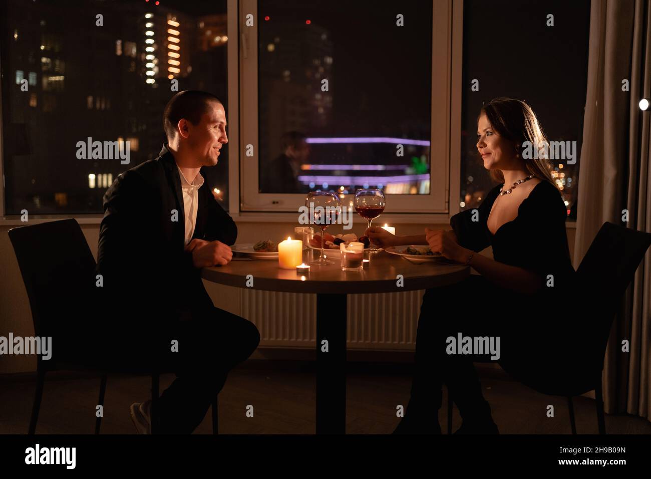 Valentinstag-Dinner bei Kerzenschein, verliebter Partner an einem Date, nächtliche Begegnung von Mann und Frau mit Wein, romantisches Date zu Hause Stockfoto