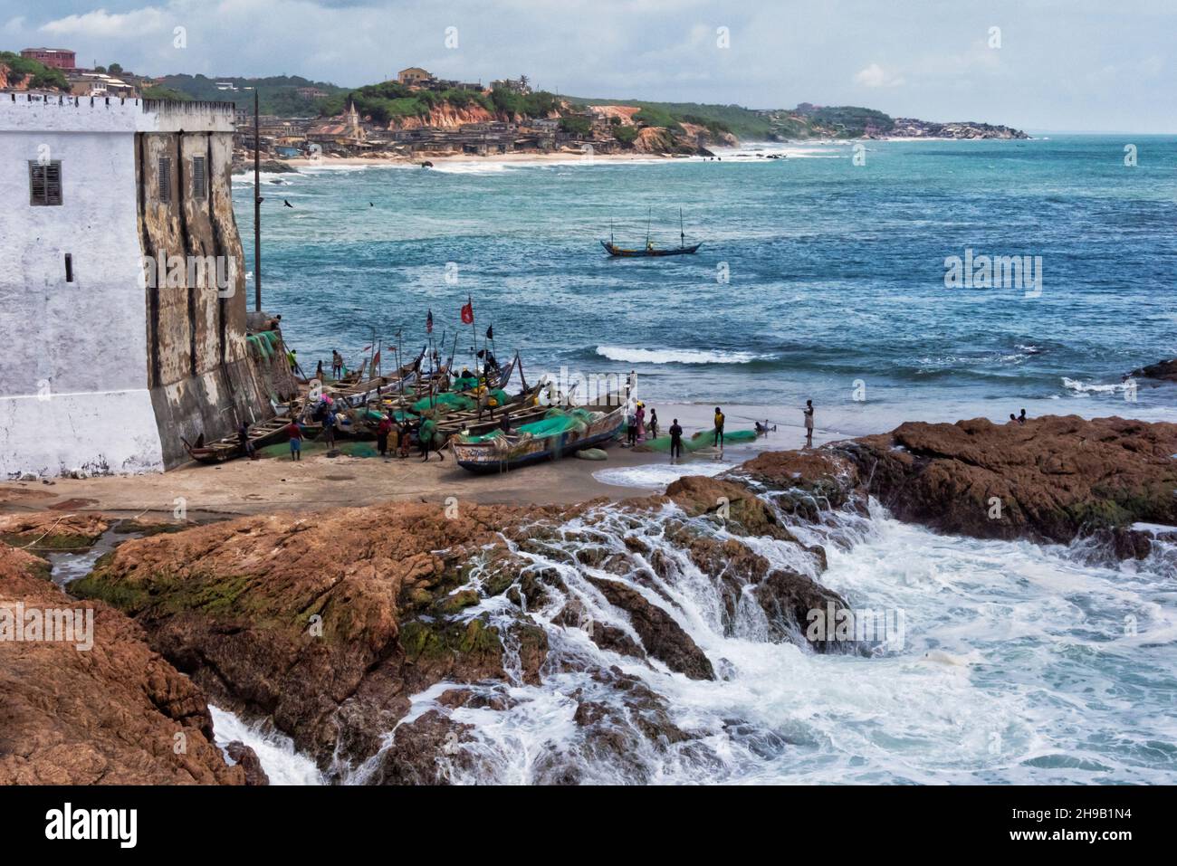 Cape Coast Castle, UNESCO-Weltkulturerbe, mit bunten Fischerbooten im Hafen, Cape Coast, Central Region, Ghana Stockfoto