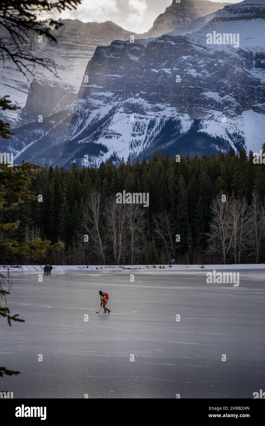 Ein Eishockey-Spieler, der einen gefrorenen Bergsee in den kanadischen Rockies in der Nähe von Banff skaten. Stockfoto