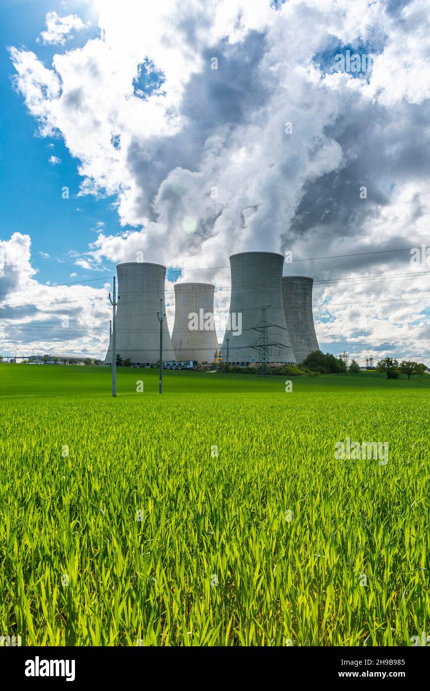 Kühlturm des Kernkraftwerks hinter grünem Gras. Atomenergie. Kernkraft und Umwelt. Stockfoto