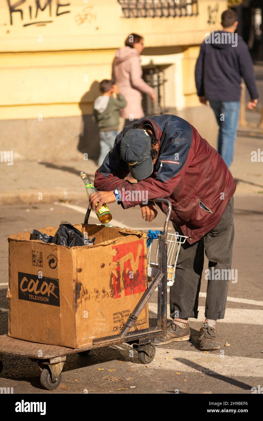 Ein Obdachloser hält eine Flasche in der Hand und schiebt einen Trolley in die Straßen. Despair-Konzept. Sofia, Bulgarien, Osteuropa, EU Stockfoto