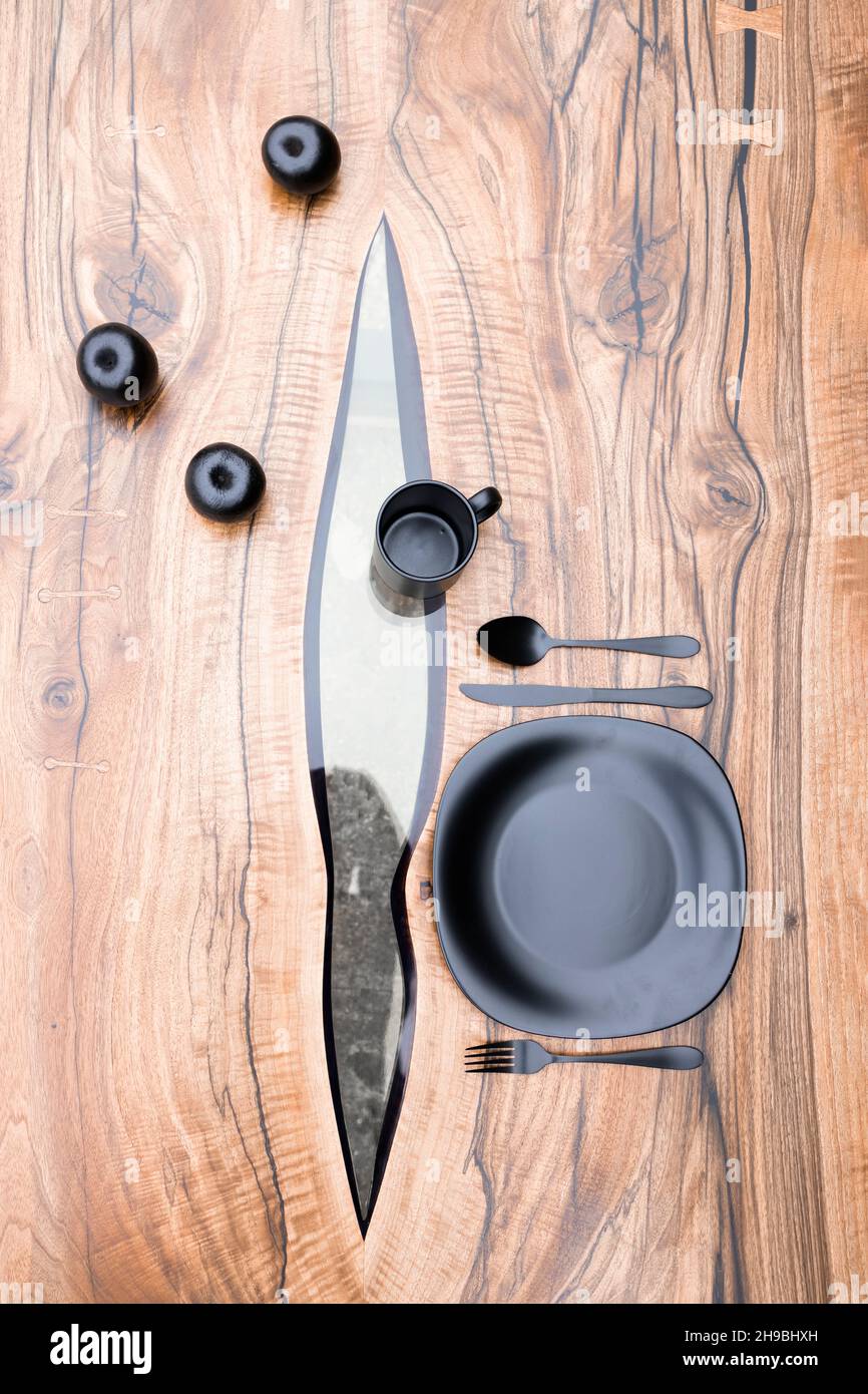 Verschiedene schwarze Gegenstände auf einem handgefertigten Tisch aus Epoxidharz Stockfoto