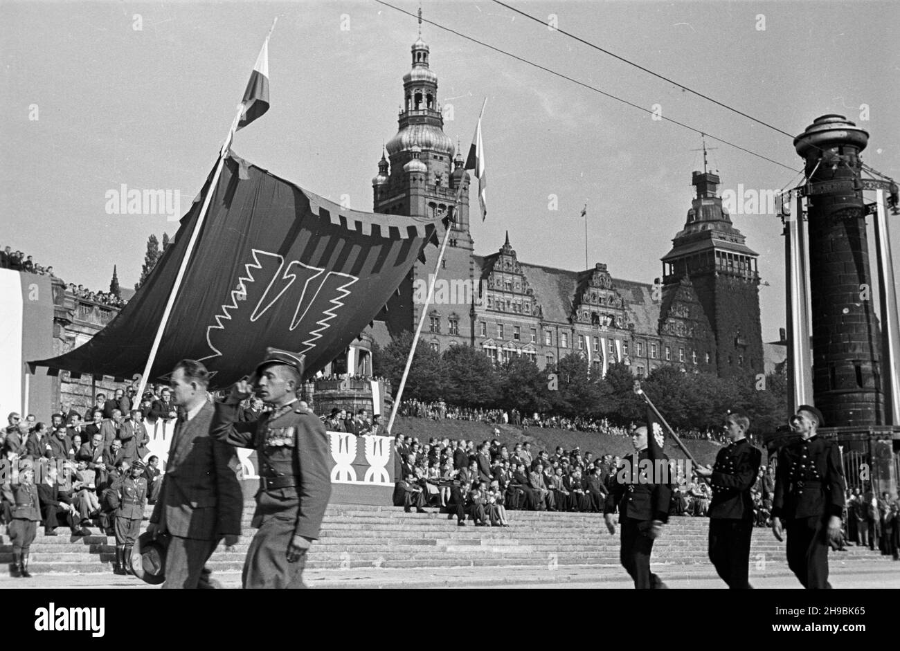 Stettin, 1947-09-07. Trzeci Zjazd Przemys³owy Ziem Odzyskanych. NZ. Defilada na Wa³ach Chrobrego. Maszeruj¹ uczniowie szkó³ przysposobienia przemys³owego. Przed nimi dyrektor szko³y i oficer Wojska Polskiego. Z lewej przedstawiciele rz¹du na trybunie honorowej. W tle widoczny gmach dawnej rejencji szczeciñskiej z lat 1901-1921. po/ms PAP Stettin, 6. September 1947. Der Industriekongress der wiedergewonnenen Gebiete von 3rd. Eine Defilade auf Waly Chrobrego. Marching Studenten der industriellen Vorbereitung Hochschulen. Auf dem linken Regierungsvertreter auf dem Paradestand. Im Hintergrund ein Fragmen Stockfoto