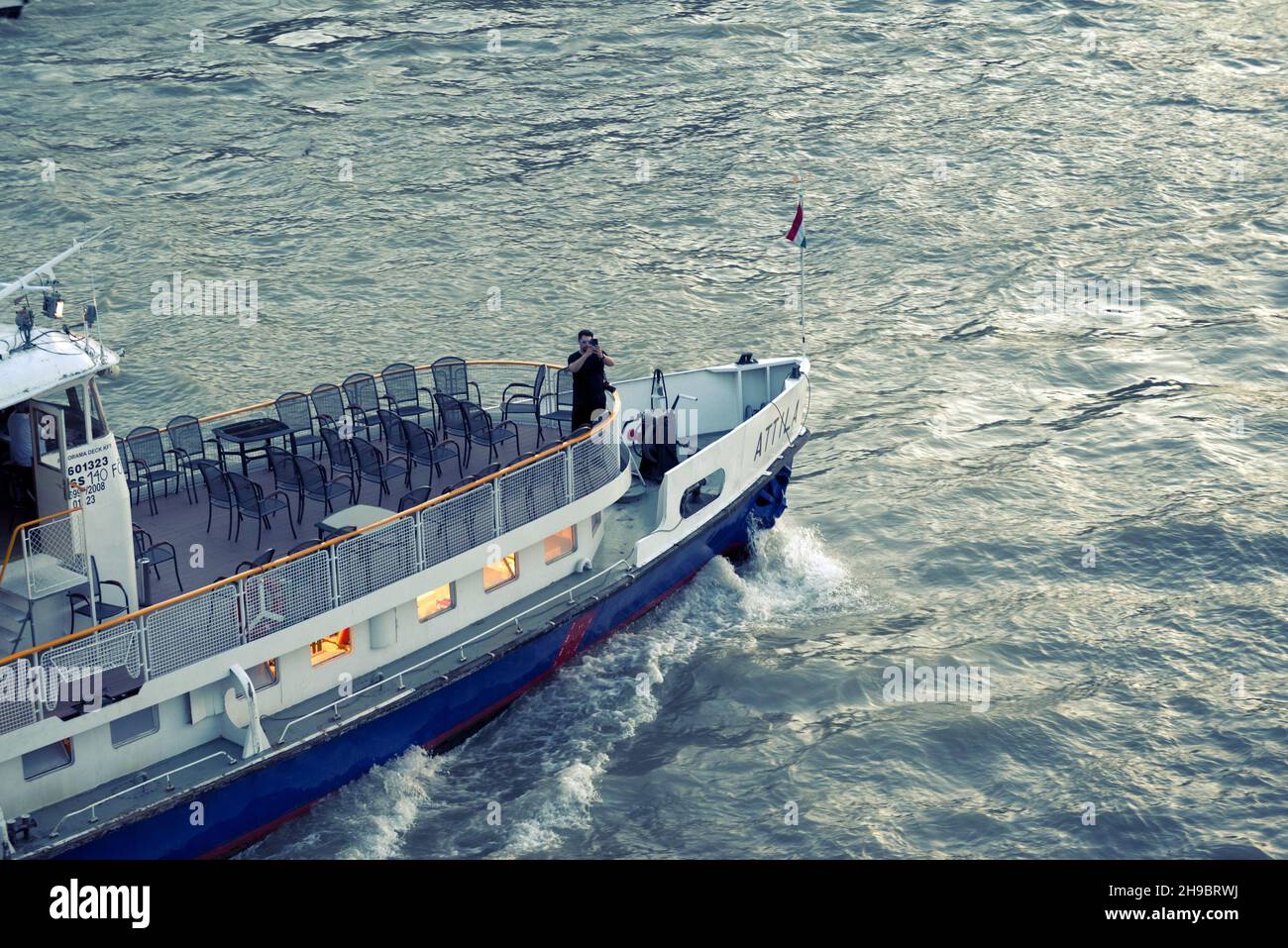 Ein Mann macht ein Foto, das auf einer Motorbootnase gegen Wasser steht Stockfoto
