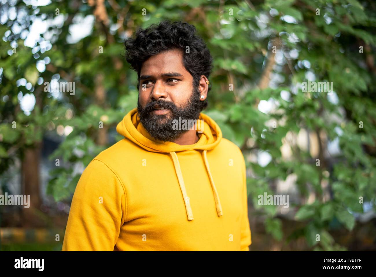 Hübsches männliches Modell in einem öffentlichen Park, indisches männliches Modell mit grünem Hintergrund Stockfoto