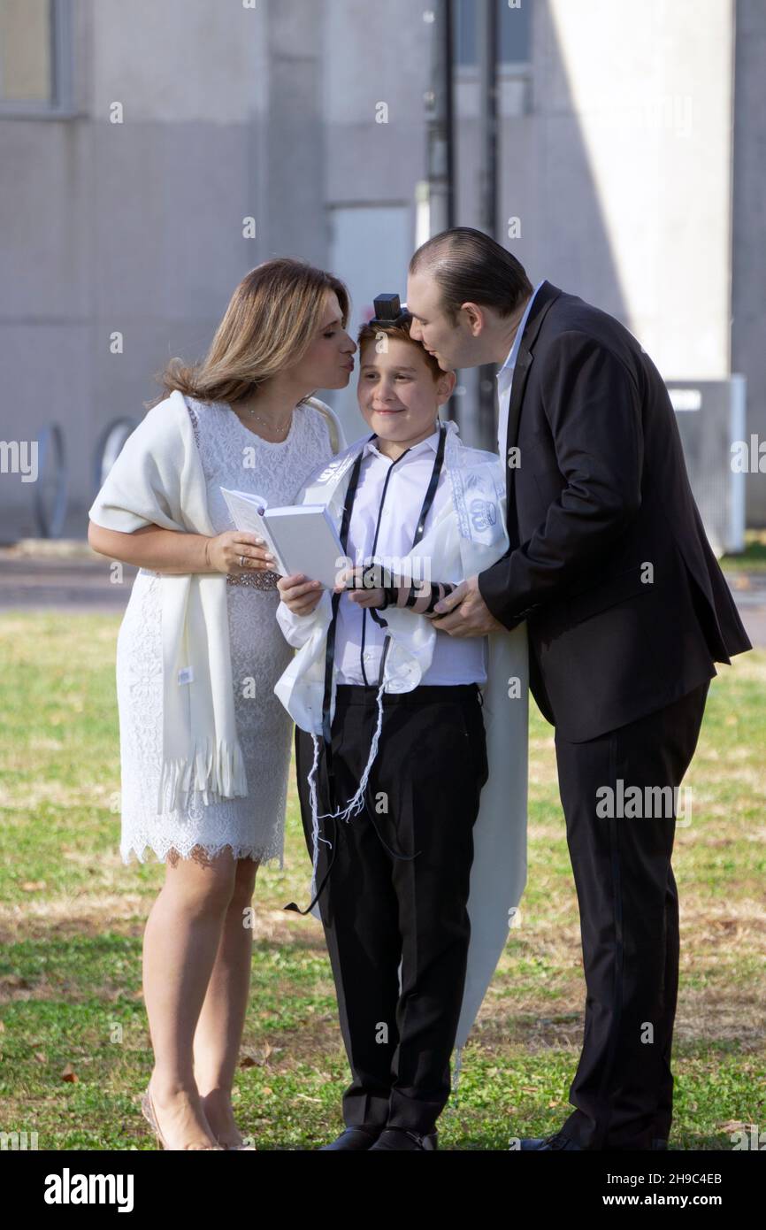 Jüdische Eltern gedenken der Bar Mitzvah ihres Sohnes mit einer Fotosession im Freien, bei der er einen tallis und Teffilin trägt. In einem Park in Queens NYC Stockfoto
