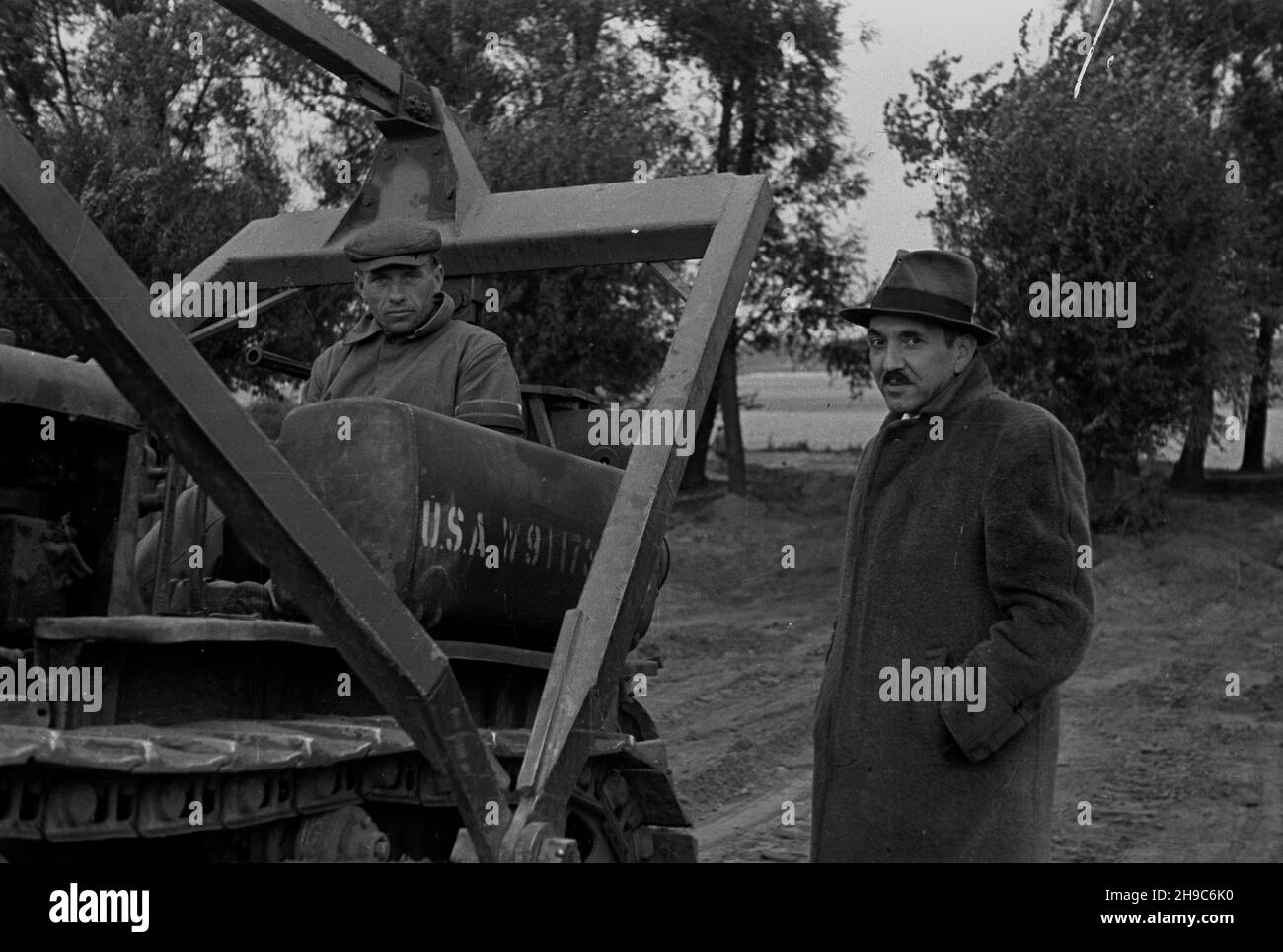 Polska, 1947-10. Wa³ przeciwpowodziowy rzeki Wis³y w rejonie Kazunia Ko³o Warszawy. Likwidowanie zniszczeñ powsta³ych podczas wiosennej powodzi. NZ. Jeden z delegatów oceniaj¹cych stan napRAW wa³u i Operator spychacza. wb/gr PAP Dok³adny dzieñ wydarzenia nieustalony. Polen, 1947. Oktober. Weichselflutbank in der Nähe von Kazun bei Warschau. Reinigungsschäden durch das Frühlingshochwasser. Im Bild: Ein Delegierter, der den Fortschritt der Reparaturarbeiten beurteilt, und ein Planierraupen-Betreiber. wb/gr PAP Stockfoto