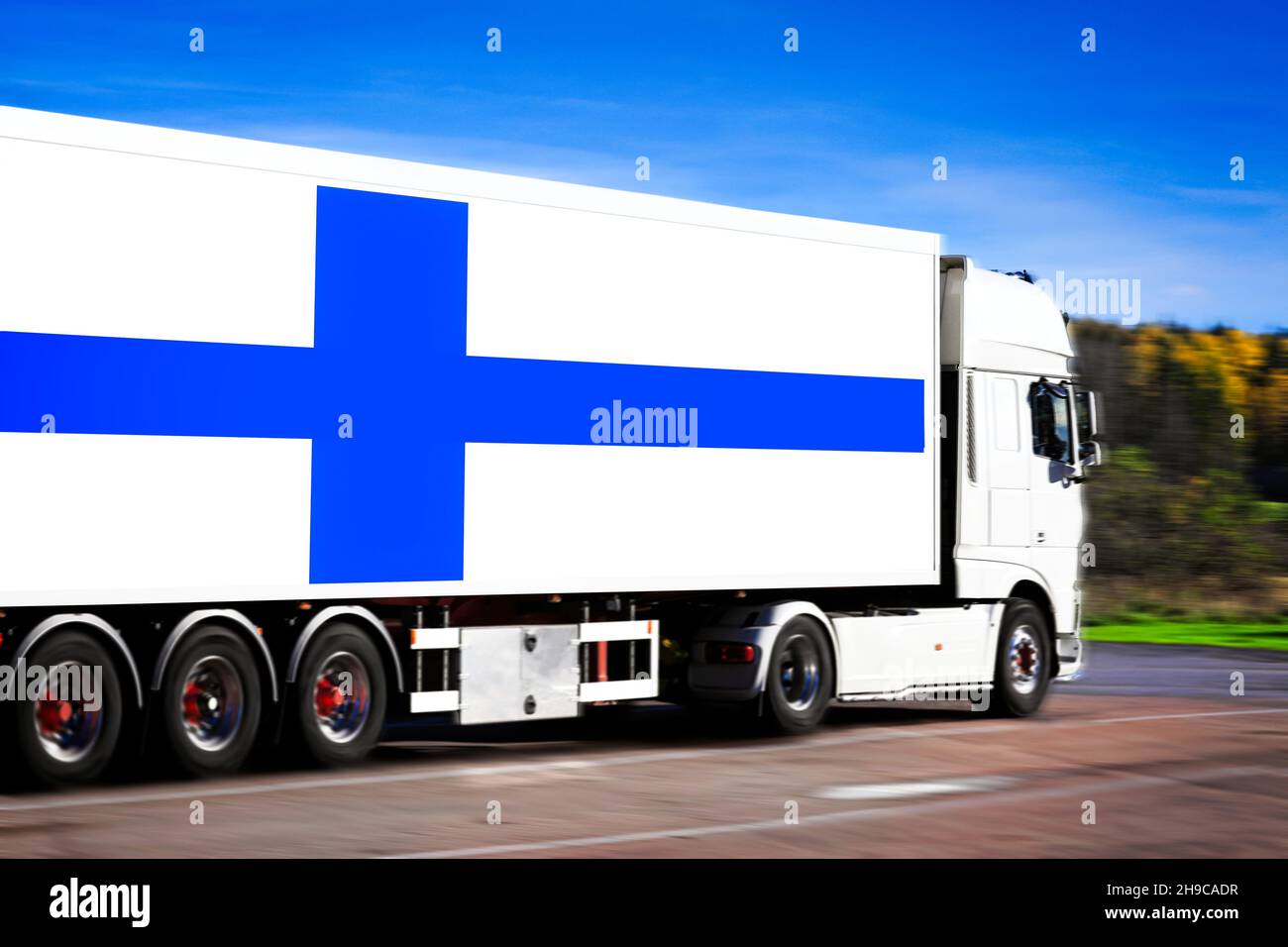 Weißer Sattelanhänger mit der Flagge Finnlands, die von einem leeren Lastwagen in Bewegung gezogen wird, Bewegungsunschärfeeffekte. Stockfoto