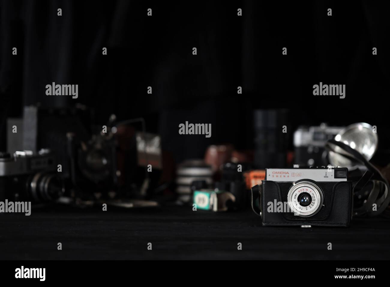 KHARKOV, UKRAINE - 27. APRIL 2021: Smena 8m Filmkamera und eine weitere alte Retro-Fotoausrüstung auf schwarzem Holztisch in der Dunkelkammer des Fotografen. Ph Stockfoto