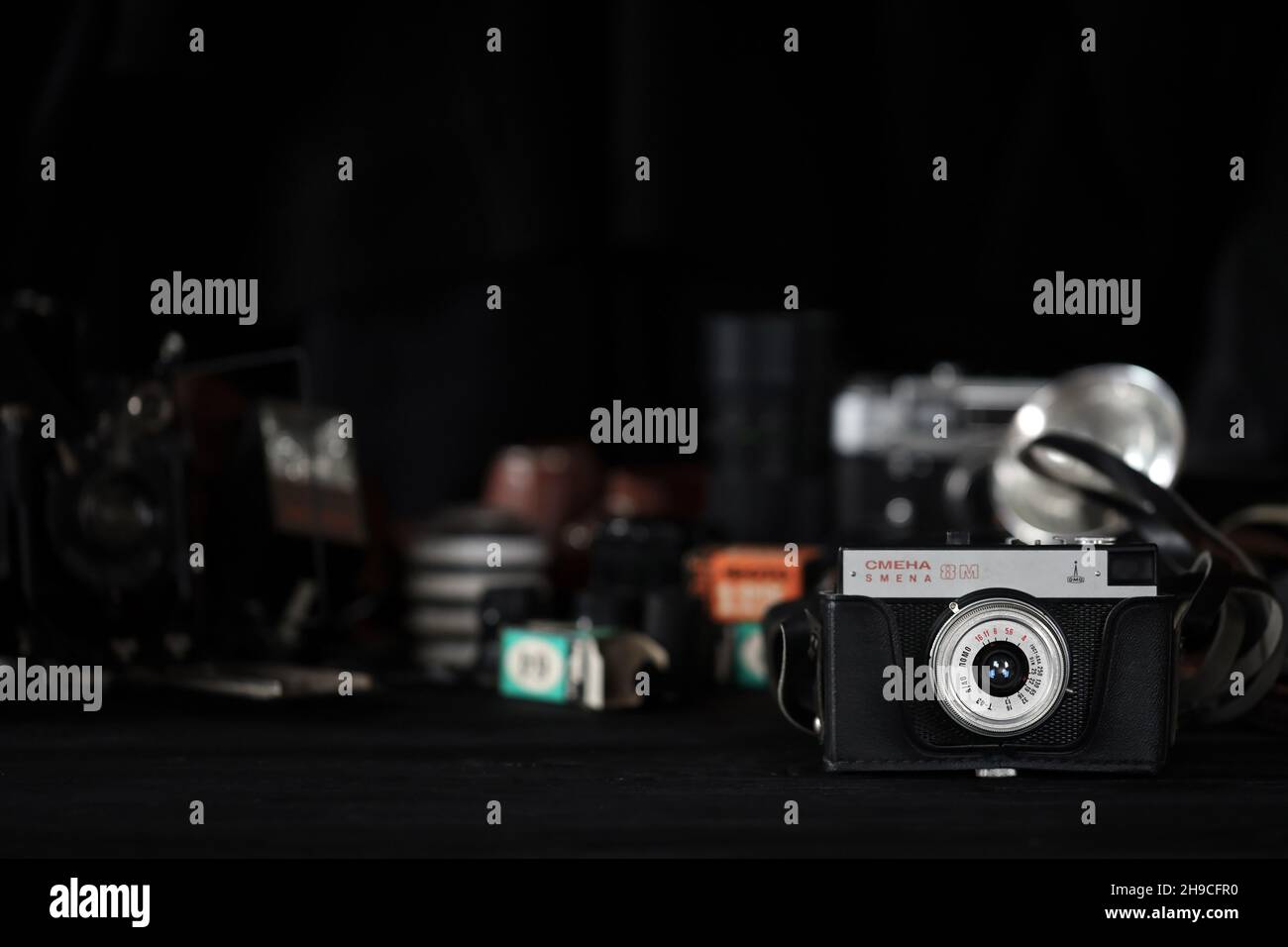 KHARKOV, UKRAINE - 27. APRIL 2021: Smena 8m Filmkamera und eine weitere alte Retro-Fotoausrüstung auf schwarzem Holztisch in der Dunkelkammer des Fotografen. Ph Stockfoto