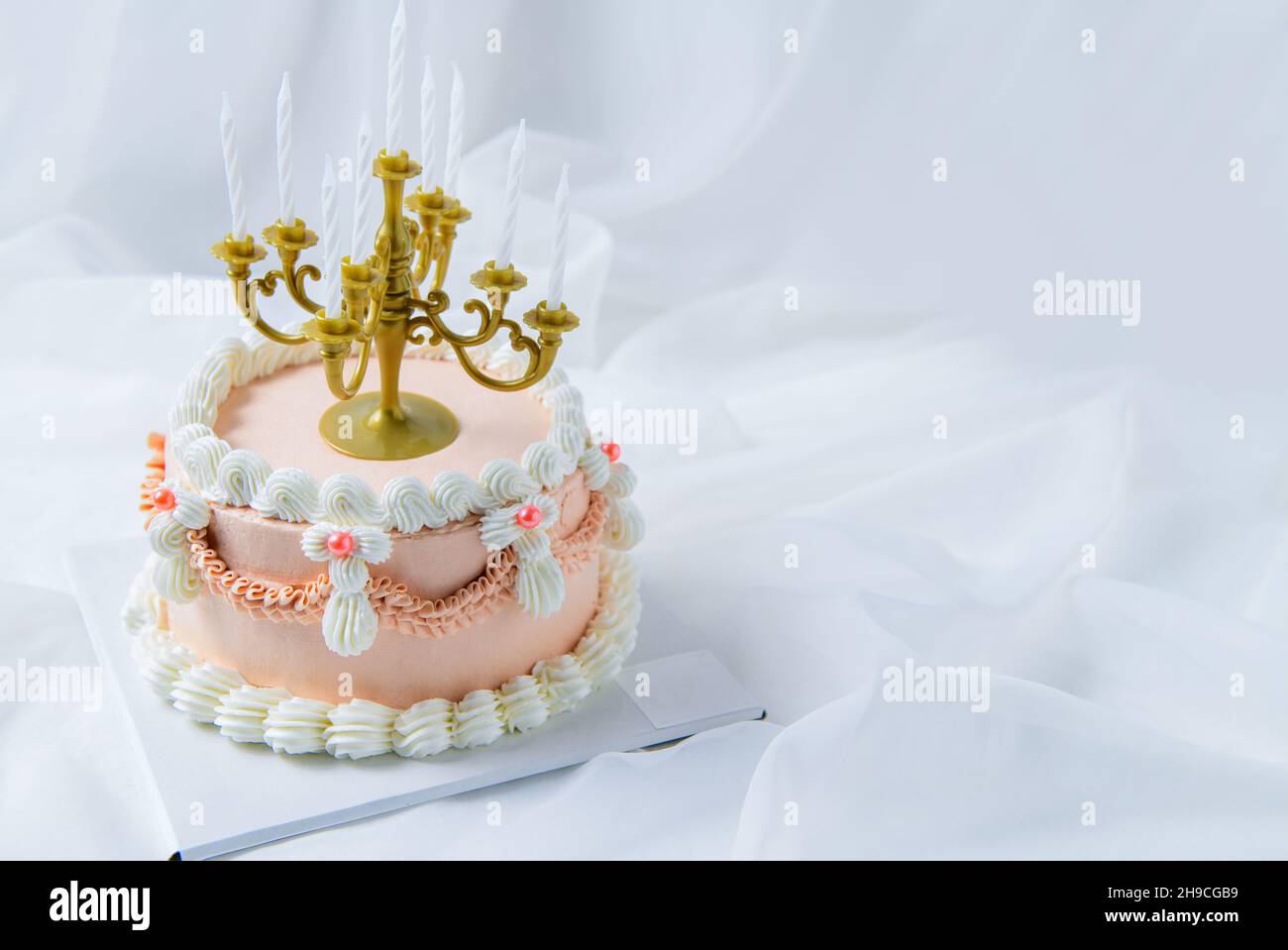 Hellrosa Vintage Butter Cremekuchen mit Kerze auf weißem Stoff Hintergrund, Luxus-Kuchen-Konzept Stockfoto