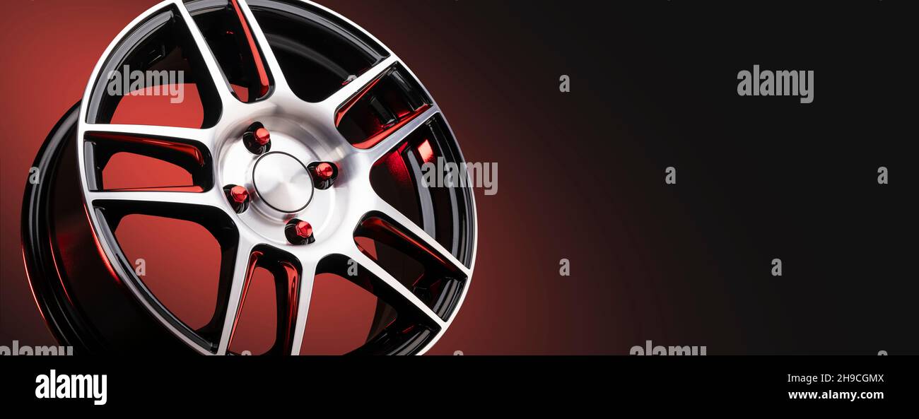 Das neue Leichtmetallrad ist leicht und sportlich rot mit glänzenden Speichen auf schwarzem Hintergrund, schönen roten Muttern Radbefestigungen. Copyspace Panorama Stockfoto