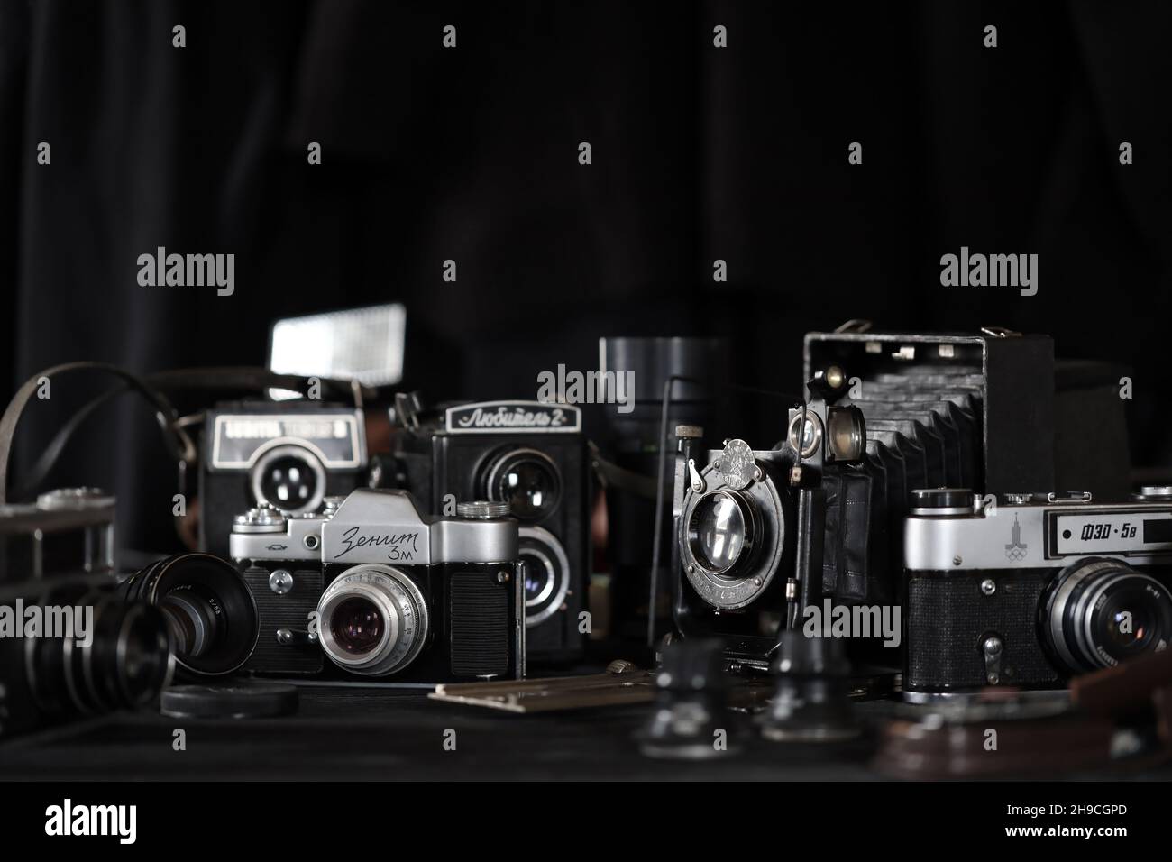 CHARKOV, UKRAINE - 27. APRIL 2021: Filmkameras und eine andere alte Retro-Fotoausrüstung auf schwarzem Holztisch in der Dunkelkammer des Fotografen. Foto Stockfoto