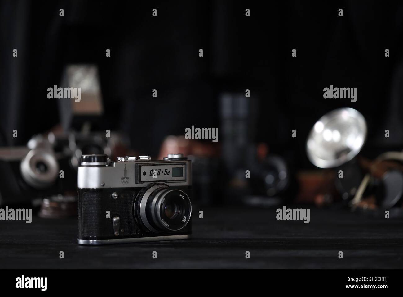 CHARKOV, UKRAINE - 27. APRIL 2021: Fed 5b Filmkamera und eine weitere alte Retro-Fotoausrüstung auf schwarzem Holztisch in der Dunkelkammer des Fotografen. Phot Stockfoto