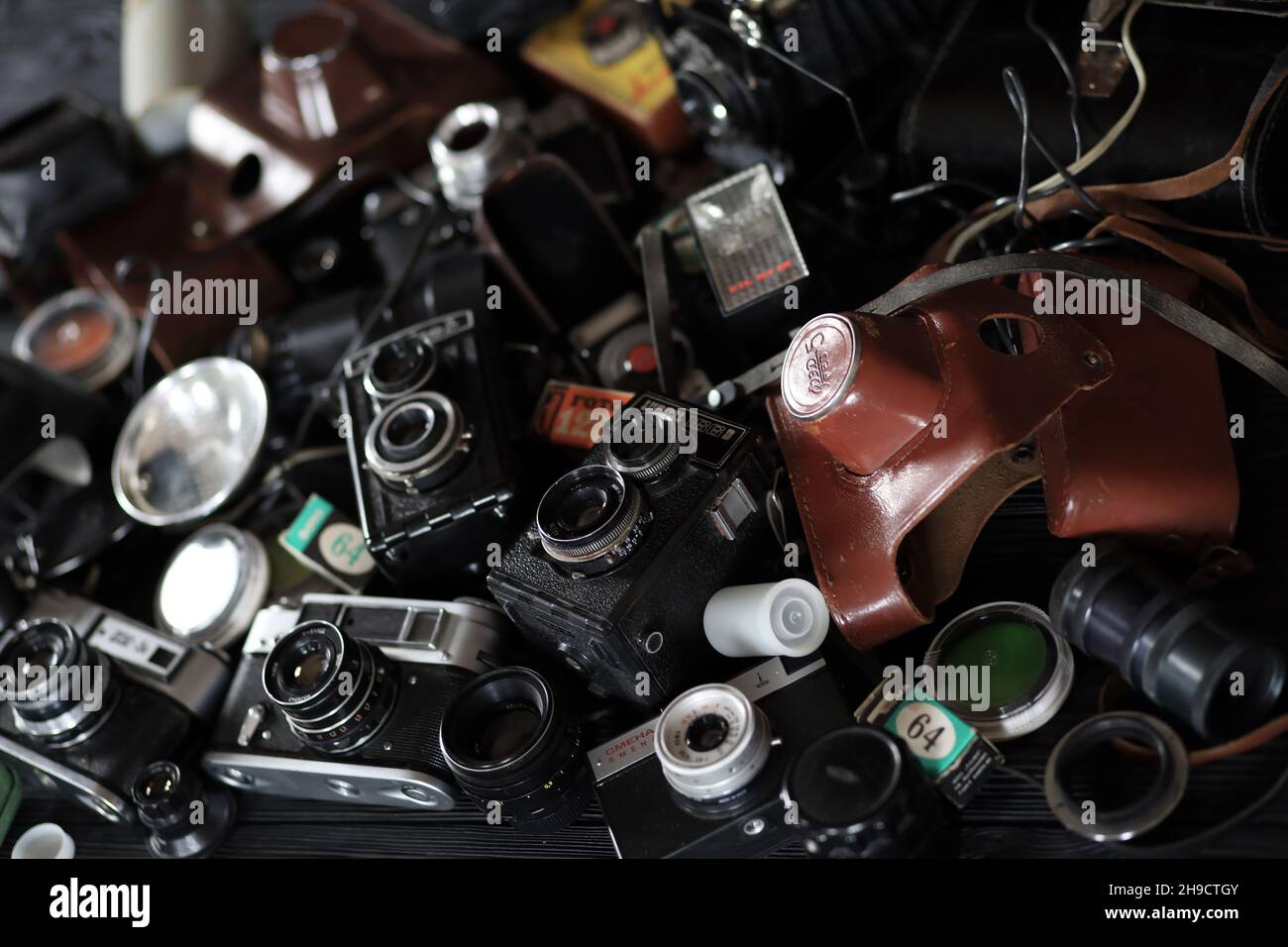 CHARKOV, UKRAINE - 27. APRIL 2021: Filmkameras und eine andere alte Retro-Fotoausrüstung auf schwarzem Holztisch in der Dunkelkammer des Fotografen. Foto Stockfoto