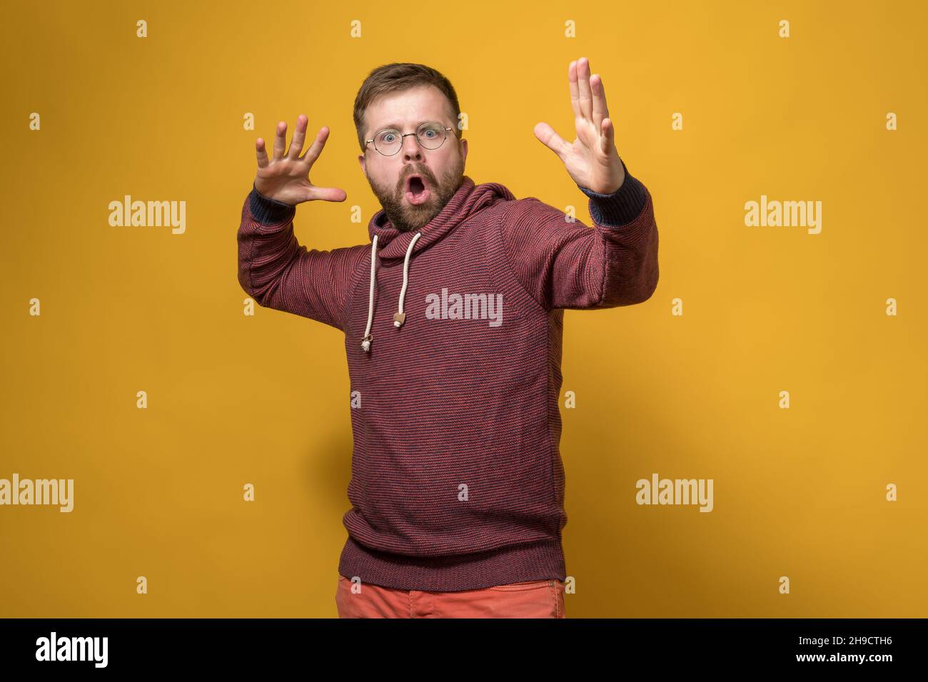 Schockierter Mann macht eine entrüstete Handbewegung und schwört auf jemanden. Gelber Hintergrund. Stockfoto