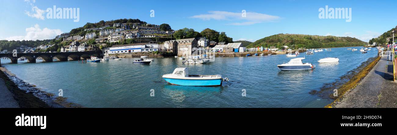 Der Hafen in Looe Cornwall zeigt die Wohnungen auf den Hügeln, die die vielen auf dem Wasser verankerten Boote und die Brücke umgeben Stockfoto