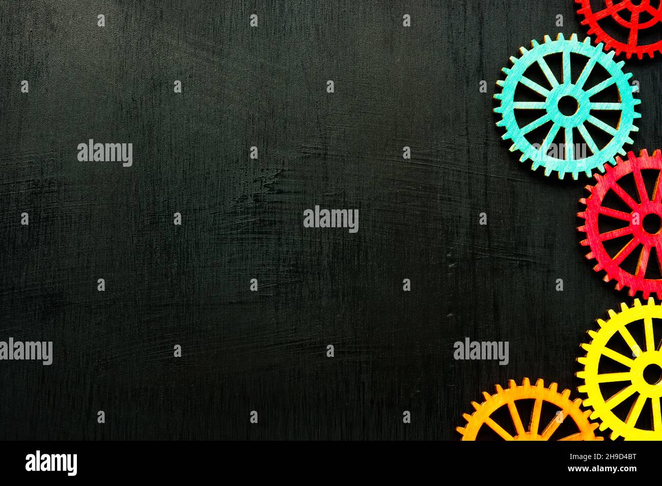 Bunte Zahnräder auf der dunklen Oberfläche und leeren Raum. Stockfoto
