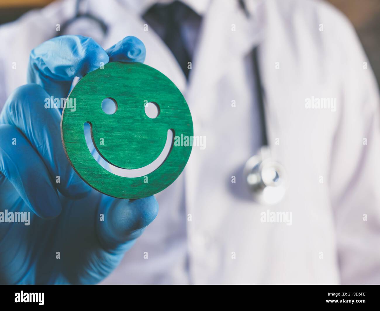 Konzept der Patientenerfahrung. Der Arzt hält ein Smiley als Symbol der Zufriedenheit. Stockfoto