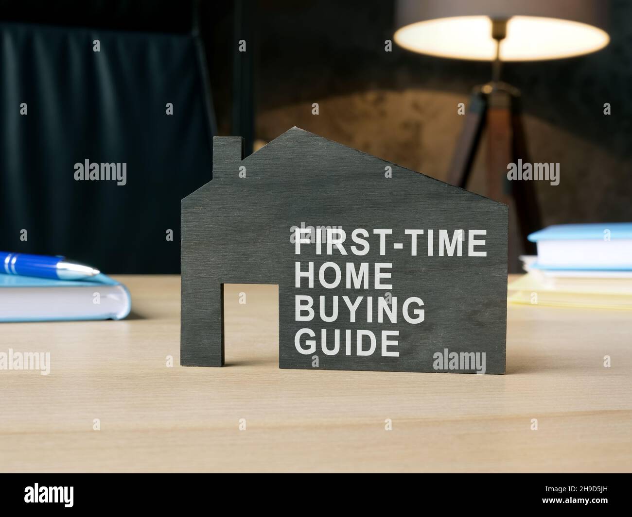 Dunkles Modell des Hauses mit Schild zum ersten Mal zu Hause kaufen Führer. Stockfoto