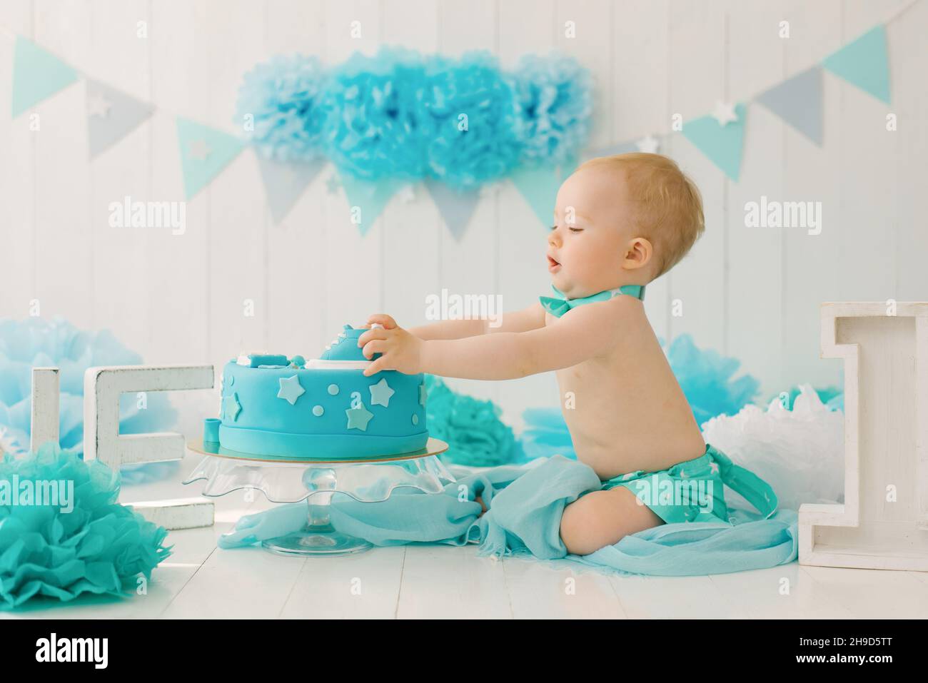 Ein einjähriger Junge probiert seinen ersten Geburtstagskuchen Stockfoto