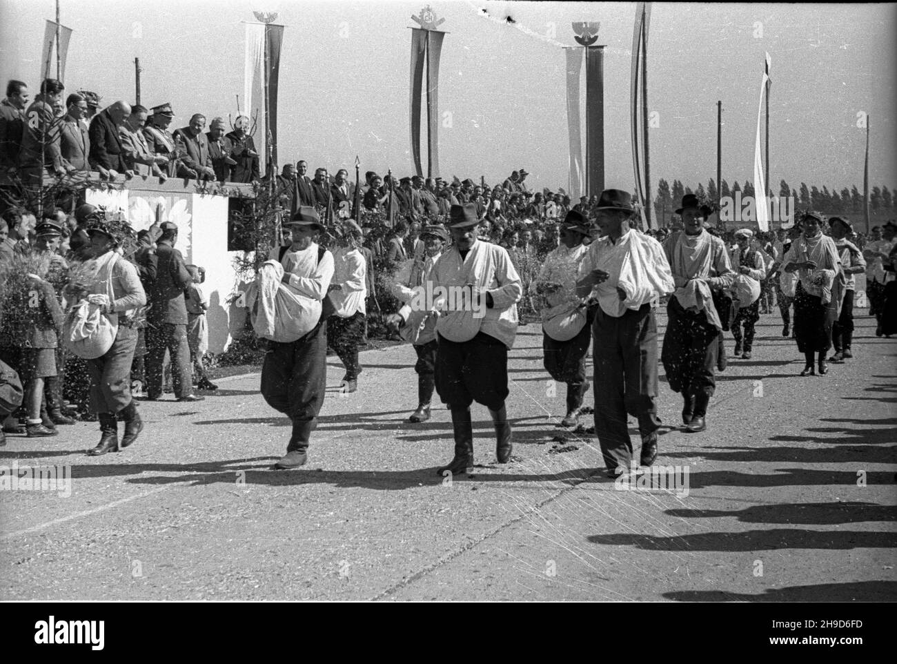 Opole, 1947-09-14. Ogólnopolskie obchody Œwiêta Plonów, do¿ynki. Defilada na miejskich b³oniach. NZ. parada siewców. Na trybunie honorowej widoczni w pierwszym rzêdzie wojewoda œl¹sko-d¹browski Aleksander Zawadzki (2L), Premier Józef Cyrankiewicz (3L), Prezydent Boles³aw Bierut (4L), marsza³ek Polski Micha³ Rola-¯ymierski (5L), wiczes epremier Antoni Korzycnyki (6L), Minister Samrolnicopusz i-Reform Kocio³ (7L) Ch³opskiej Stanis³aw 8L (D¹b. Januar). W drugim rzêdzie wiceminister rolnictwe Stanis³aw Tkaczow (1L). po/mgs PAP Opole, 14. September 1947. Nationale Erntefeier Stockfoto