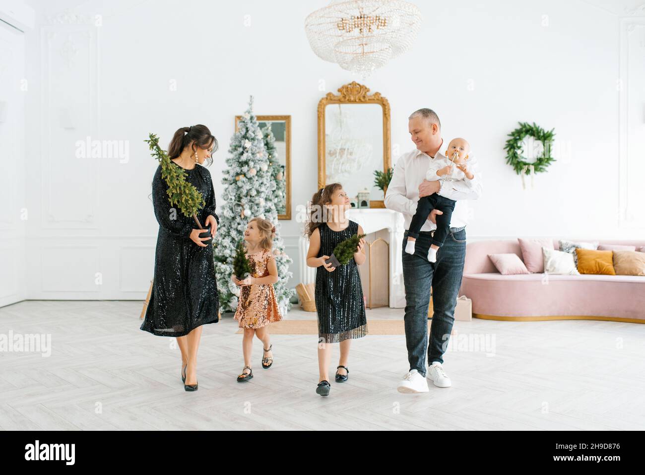 Eine junge Familie mit drei Kindern bereitet sich auf Weihnachten und Neujahr vor. Sie schmücken ihr Haus für den Urlaub Stockfoto