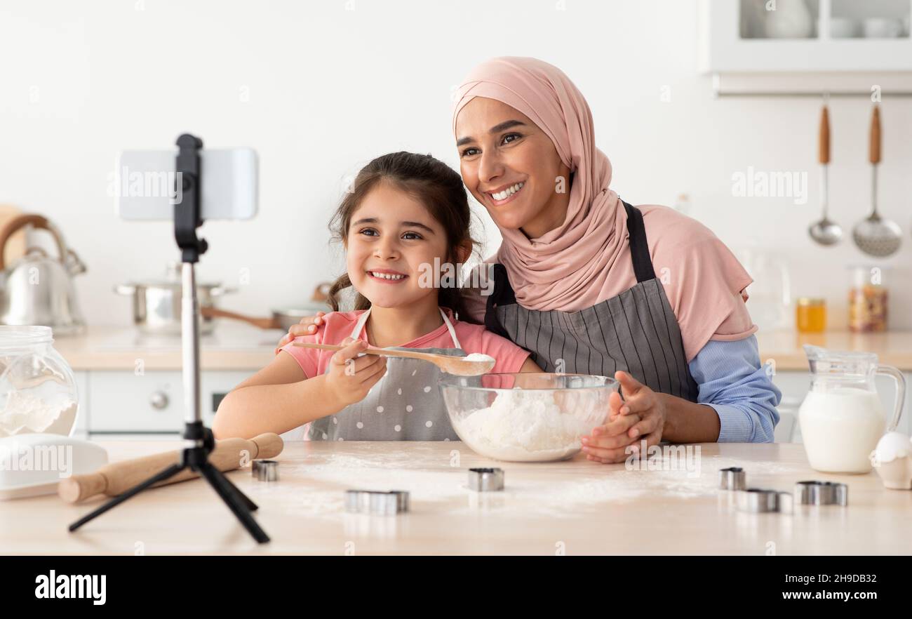 Islamische Dame Mit Kleiner Tochter Aufnahme Video Für Lebensmittel-Blog In Der Küche Stockfoto