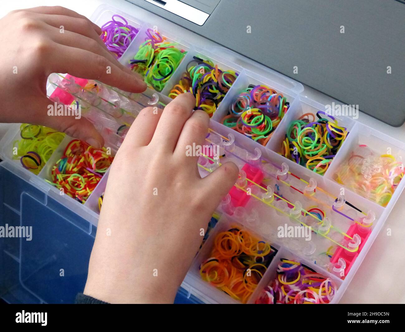 Bunte Regenbogen Webgummibänder in einer Box, Hände auf Stockfoto