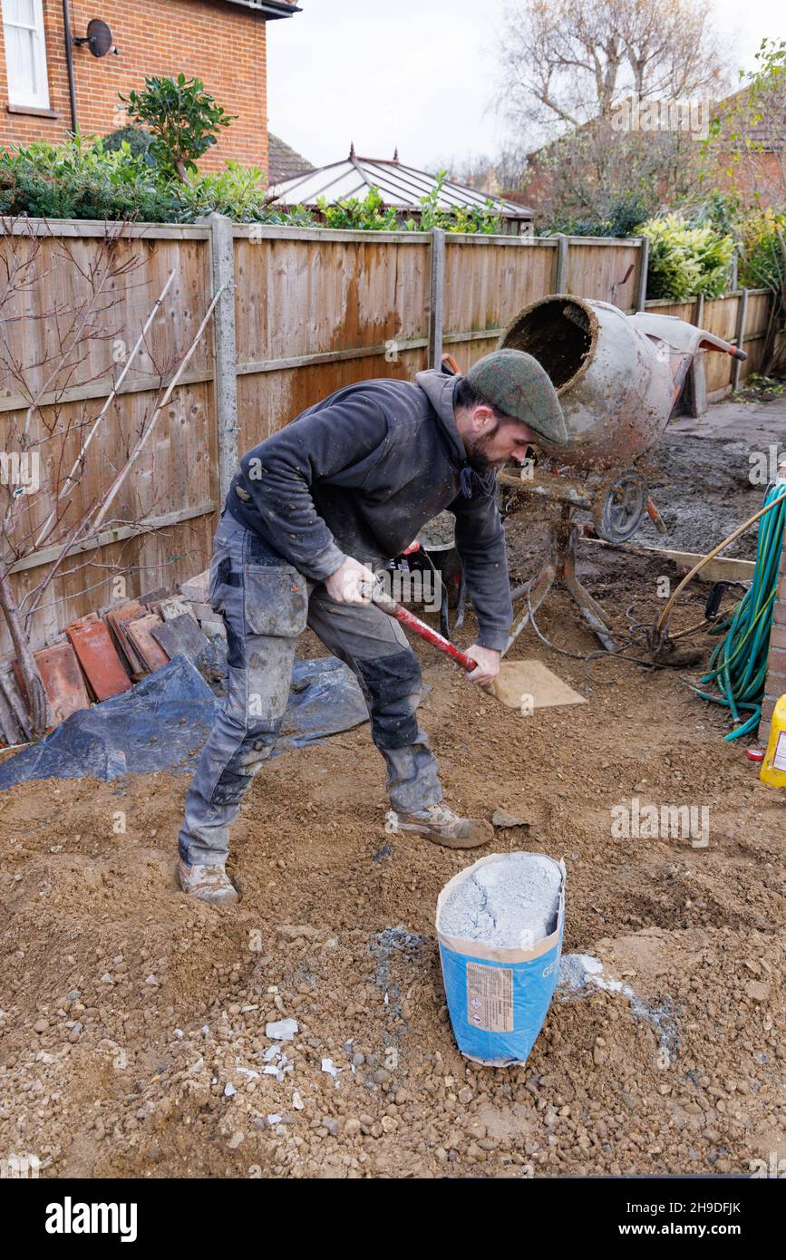 Ein Baumeister, der Zement in einem Zementmischer macht, Beispiel eines Arbeiters, der Handarbeit macht; Bauarbeiten, auf einer Baustelle, England, Großbritannien Stockfoto