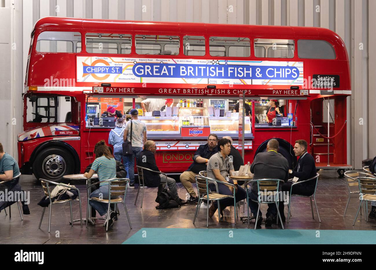 Traditionelles Essen in Großbritannien; Menschen essen Fisch und Chips aus dem Great British Fish & Chips Bus auf der Photography Show, NEC Birmingham UK Stockfoto