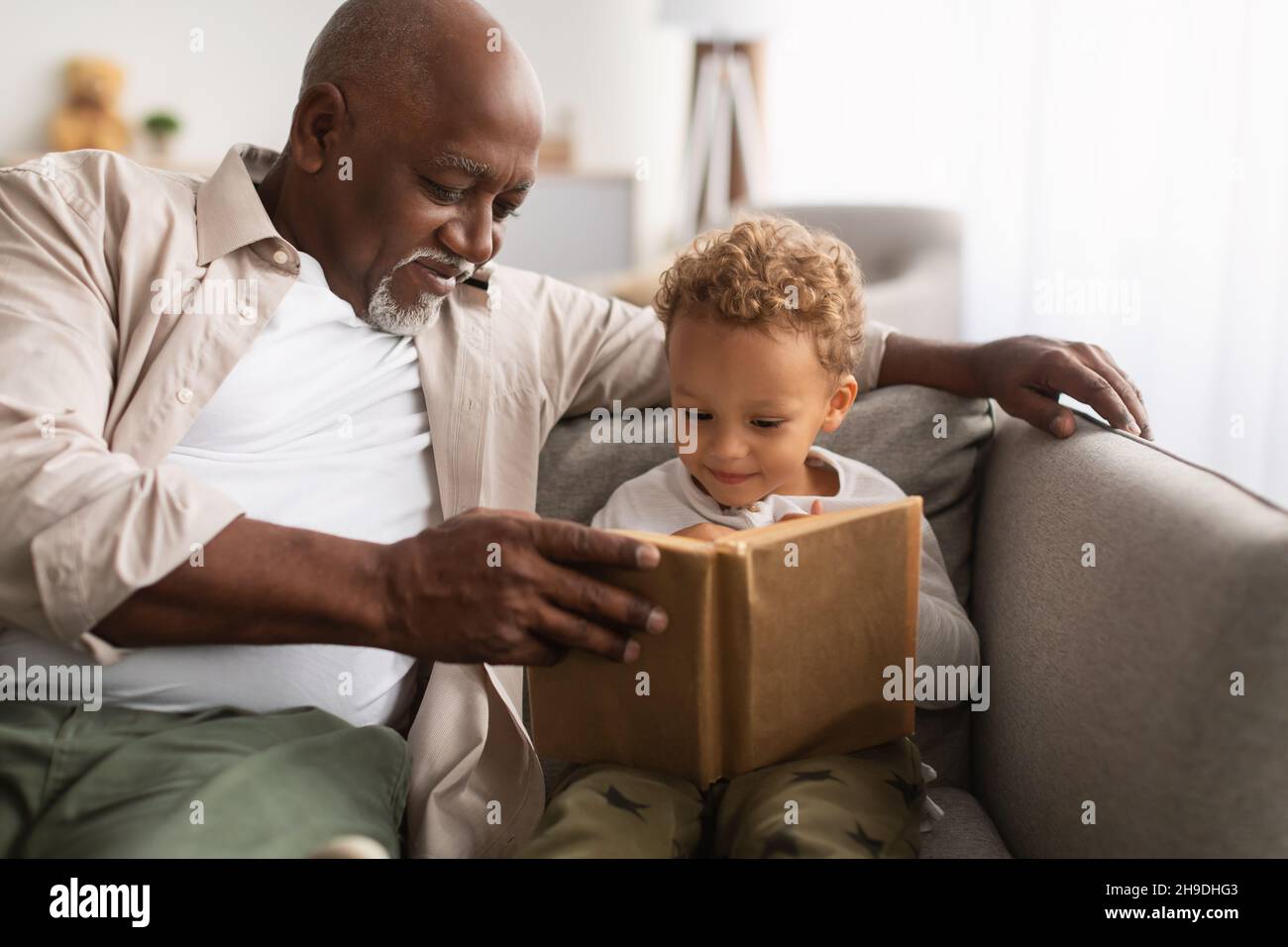 Schwarzer Großvater und Enkel beim gemeinsamen Lesen Eines Buches zu Hause Stockfoto