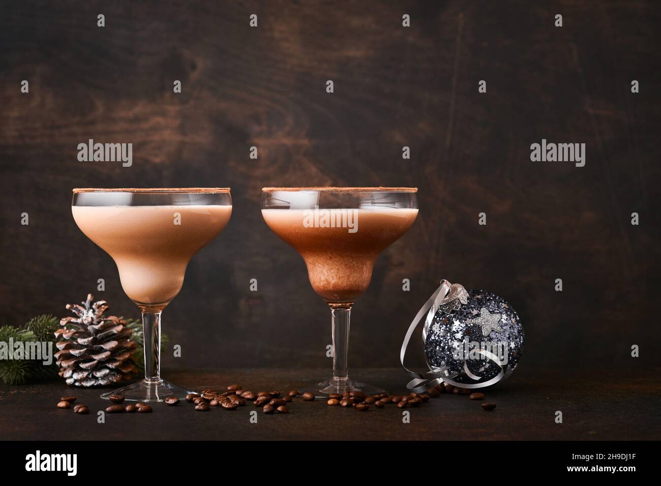 Alexander Cocktail in Cocktailglas auf Holztisch mit Shaker, Muskatnuss und kleiner Reibe mit weihnachtlicher Dekoration auf dunklem Hintergrund. Getränkefoto Stockfoto