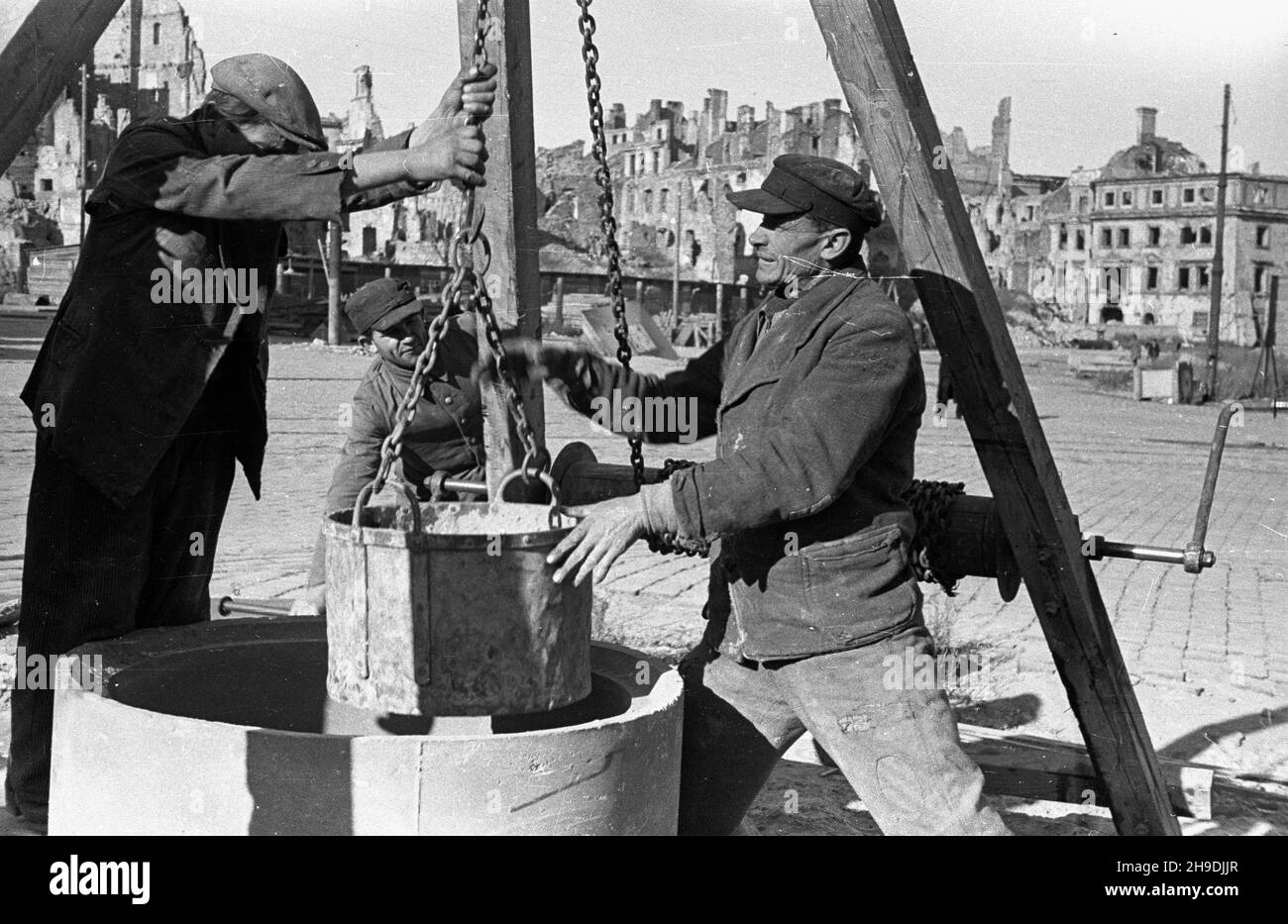 Warszawa, 1947-10. Odbudowa pa³acu Pod Blach¹. NZ. Robotnicy wydobywaj¹ piasek ze studni na placu Zamkowym. W g³êbi ruiny Starego Miasta. ps/gr PAP Dok³adny dzieñ wydarzenia nieustalony. Warschau, 1947. Okt. Wiederaufbau des Pod Blacha Palastes. Im Bild: Arbeiter, die Sand aus einem Brunnen auf dem Zamkowy-Platz aufziehen. Im Hintergrund die Ruinen der Altstadt. ps/gr PAP Stockfoto