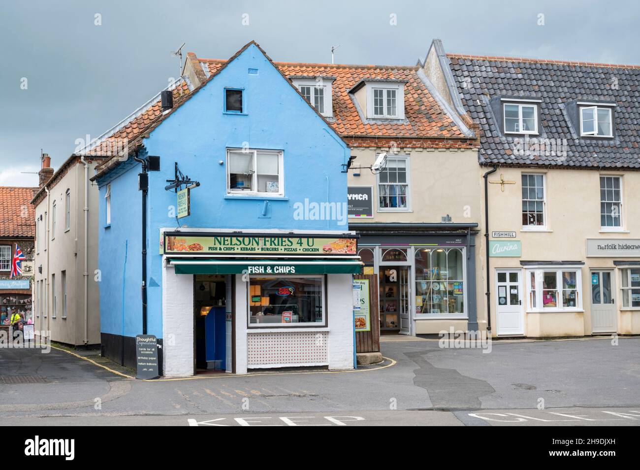 Die Hauptstraße mit Geschäften und geparkten Autos in der Marktstadt holt, Norfolk, Großbritannien Stockfoto