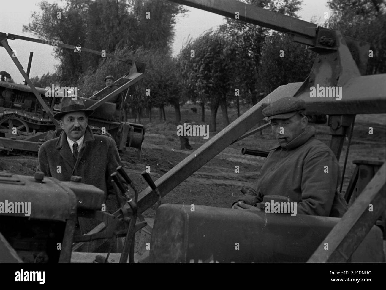 Polska, 1947-10. Wa³ przeciwpowodziowy rzeki Wis³y w rejonie Kazunia Ko³o Warszawy. Likwidowanie zniszczeñ powsta³ych podczas wiosennej powodzi. NZ. Jeden z delegatów oceniaj¹cych stan napRAW wa³u i Operator spychacza. wb/gr PAP Dok³adny dzieñ wydarzenia nieustalony. Polen, 1947. Oktober. Weichselflutbank in der Nähe von Kazun bei Warschau. Reinigungsschäden durch das Frühlingshochwasser. Im Bild: Ein Delegierter, der den Fortschritt der Reparaturarbeiten beurteilt, und ein Planierraupen-Betreiber. wb/gr PAP Stockfoto