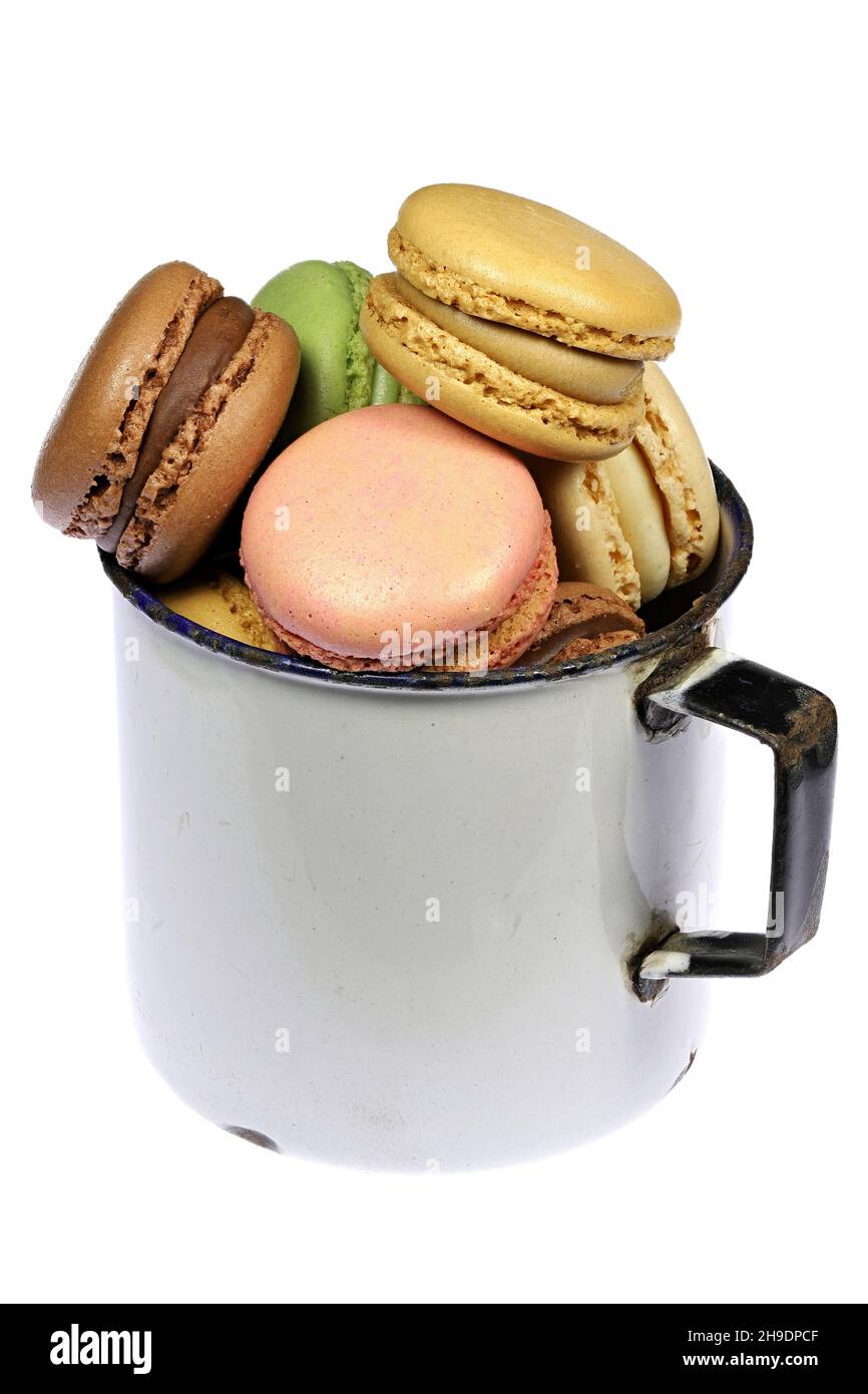 Bunte Macarons in einem Vintage emaillierten Becher auf weißem Hintergrund Stockfoto