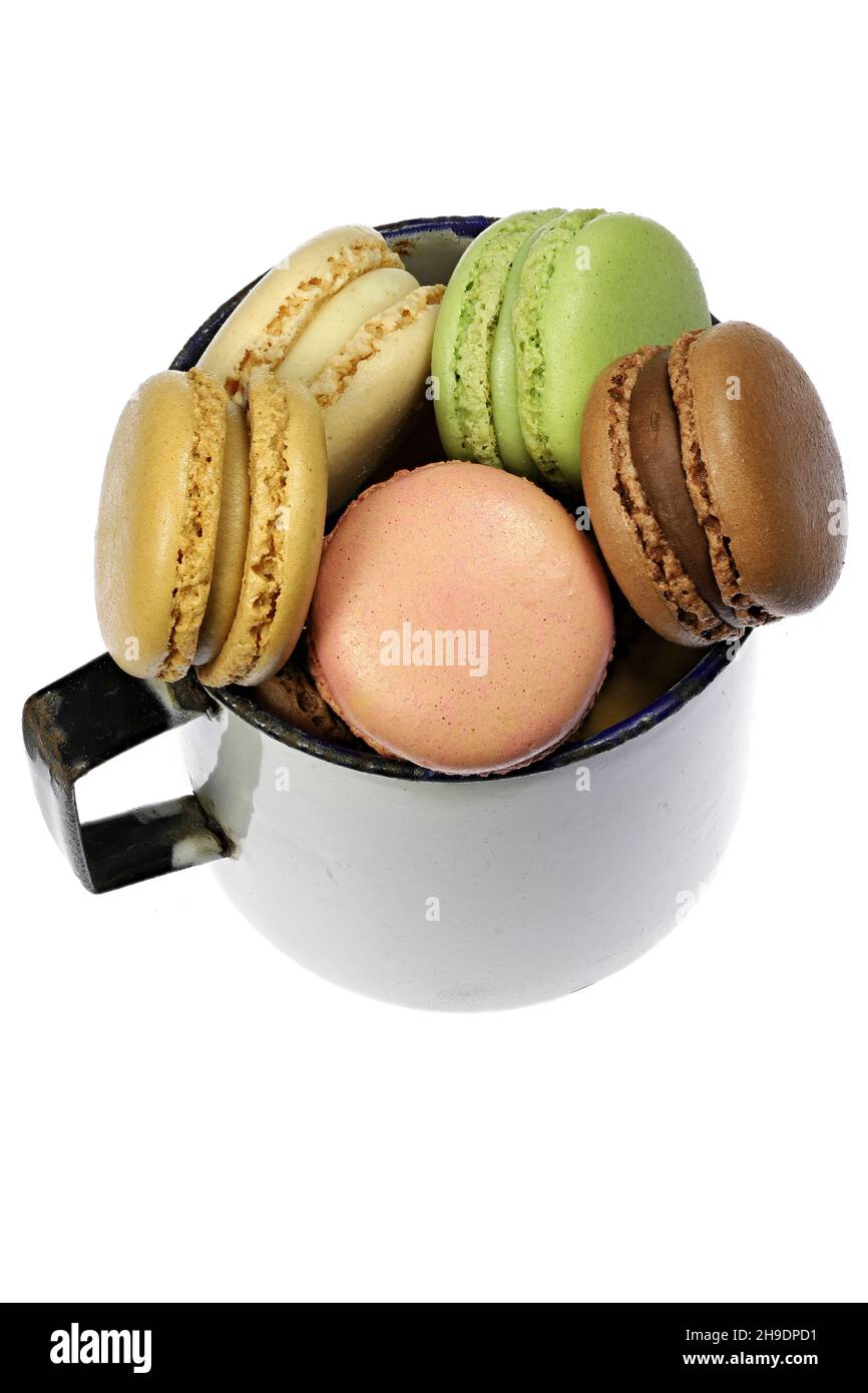 Bunte Macarons in einem Vintage emaillierten Becher auf weißem Hintergrund Stockfoto