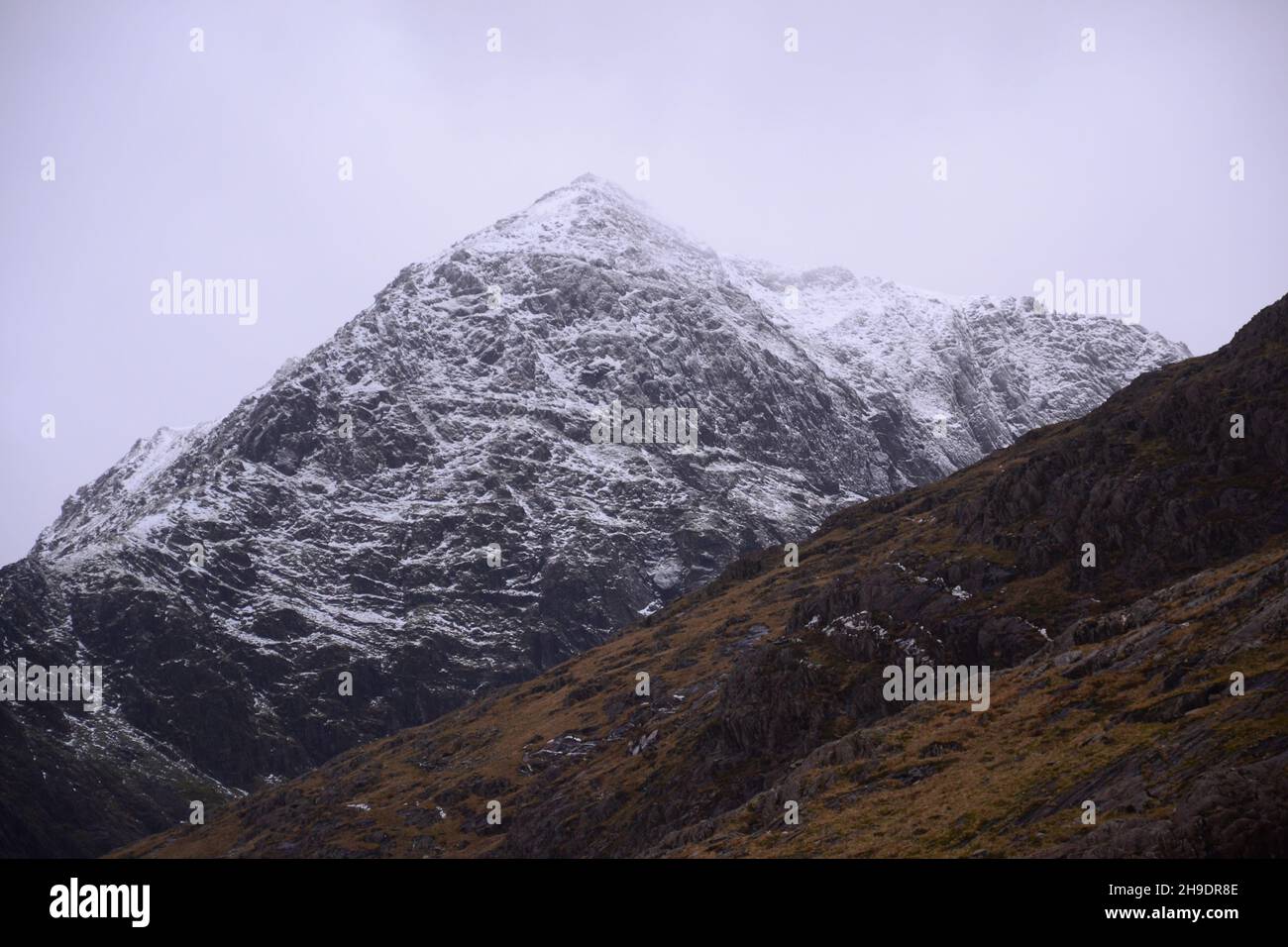 Snowdonia National Park (Eryri), Wales, Großbritannien. 6th. Dezember 2021. Schnee auf dem Gipfel des Snowdon (Yr Wyddfa), dem höchsten Berg in Wales, von der Bergarbeiterspur aus gesehen, als sich der Sturm Barra nähert. Es wird erwartet, dass Großbritannien am nächsten Tag von starken Winden und Schnee getroffen wird. Der Berg liegt 1.085 Meter (3.560 Fuß) über dem Meeresspiegel und ist der höchste Punkt der Britischen Inseln außerhalb der schottischen Highlands. Quelle: Terry Waller/Alamy Live News Stockfoto