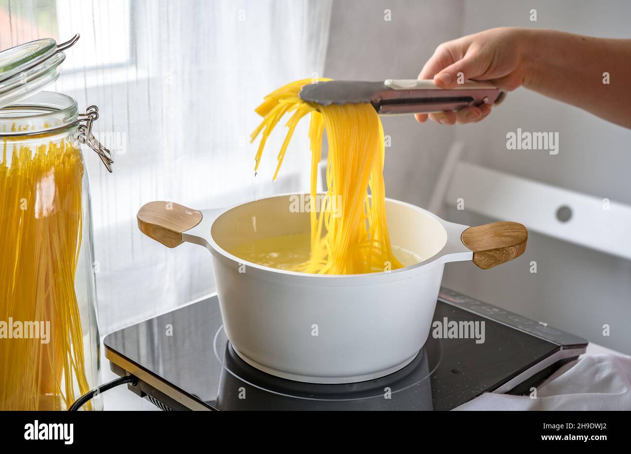 Weibliche Hand nimmt heiße Pasta aus dem Topf Stockfoto