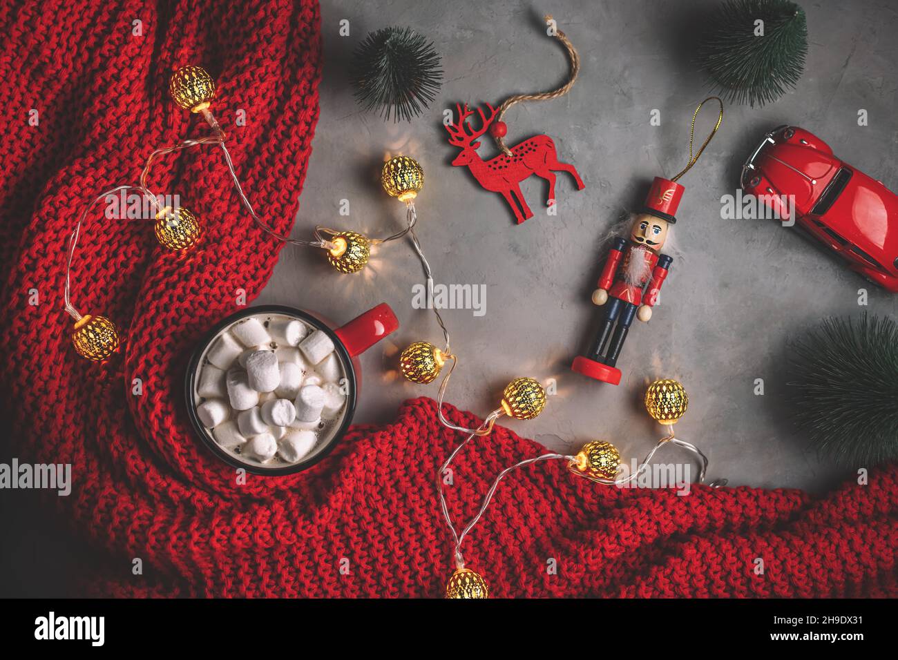 Becher mit Süssmarmelibe, Girlanden, roter Decke auf grauem Hintergrund. Neujahr, weihnachten. Spielzeug, flach liegend, Draufsicht Stockfoto