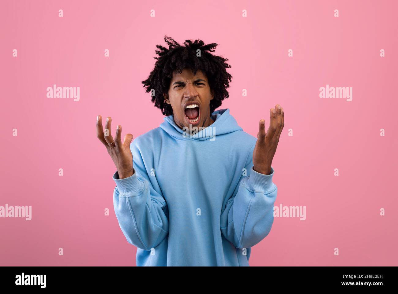 Wütender schwarzer Teenager, der vor Wut auf rosafarbenem Studiohintergrund schreit Stockfoto