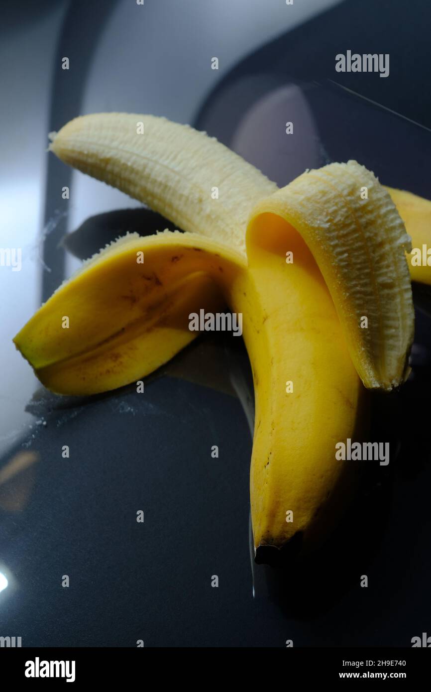 Geschälte, reife gelbe Banane auf dunklem, reflektierendem Hintergrund Stockfoto